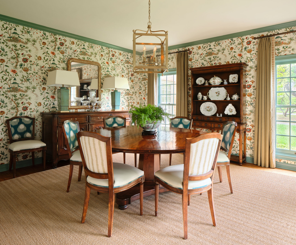 A custom cool-green paint color on the woodwork coordinates with the wallpaper in this traditional dining room.