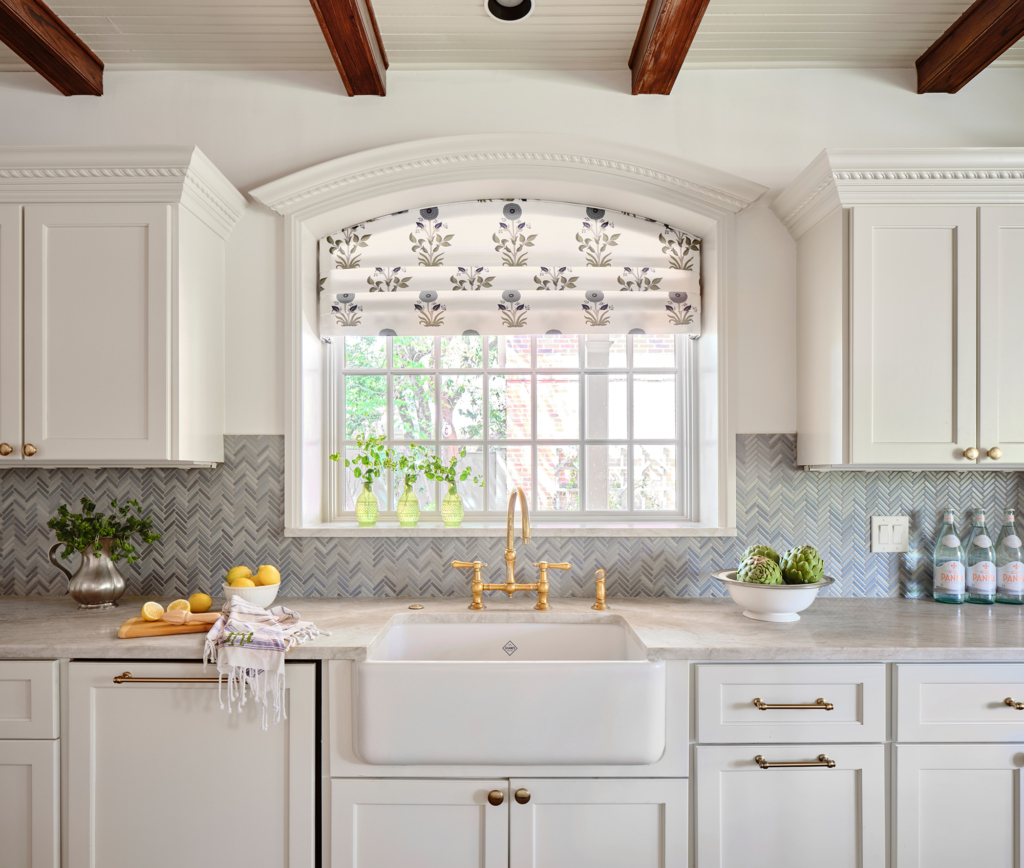 Kitchen sink area showing the stone counters, herringbone backsplash, and detailed millwork.