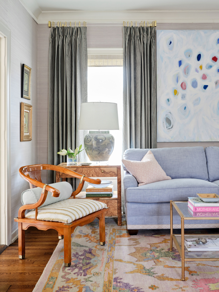 The pale blue of the wallcovering pairs perfectly with the blue sofa, drapes, and artwork.