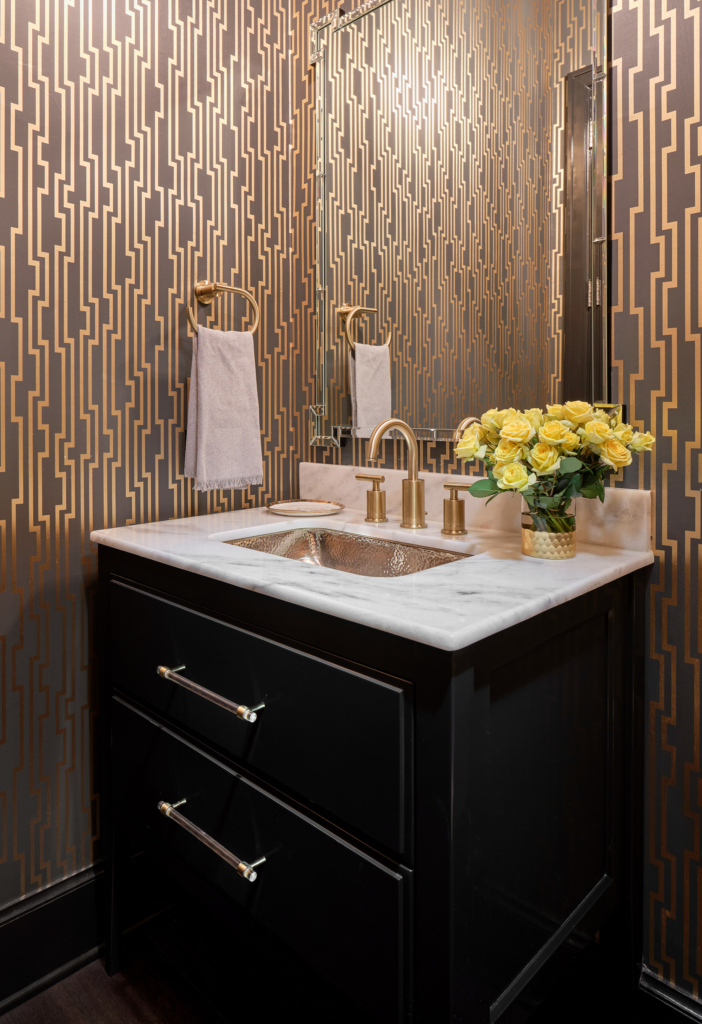 This Alamo Heights powder bath features a Thibaut wallpaper installation paired with a vanity cabinet painted in Sherwin Williams "Tricorn Black", all done by Paper Moon Painting.