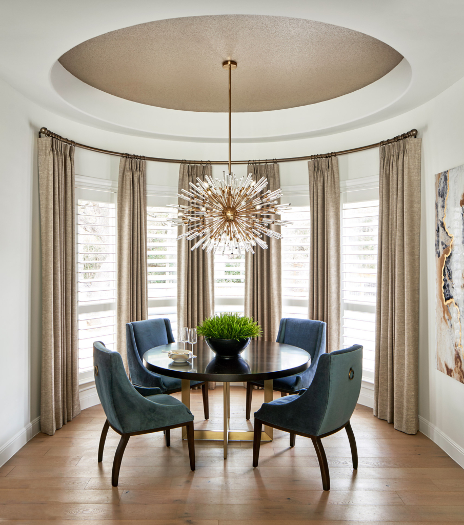 The rich blue seating, wallpapered ceiling, and sunburst chandelier make this breakfast area feel luxurious.