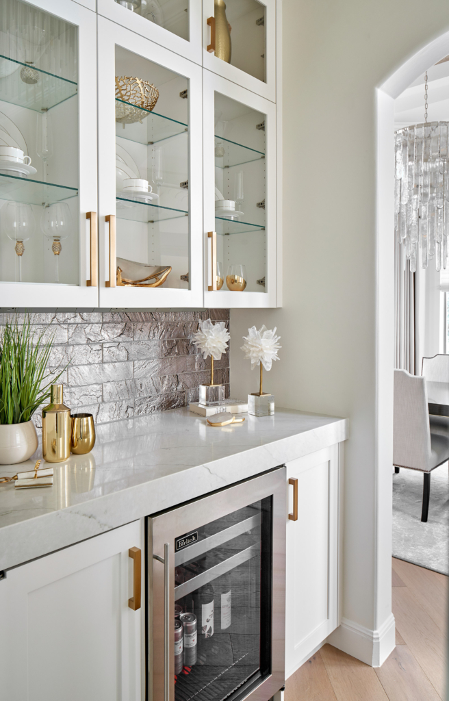 Elegant home wet bar with brass hardware and a mica tile backsplash.