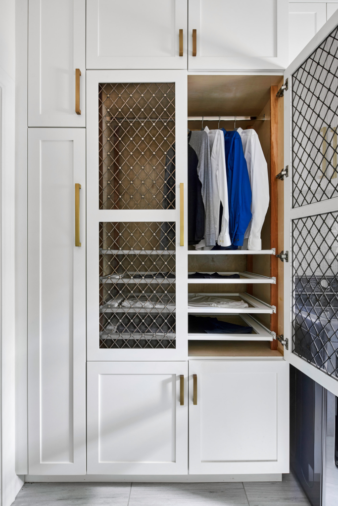 A gorgeous yet efficient laundry room with clothes drying shelves and brass mesh inserts in the cabinet doors.