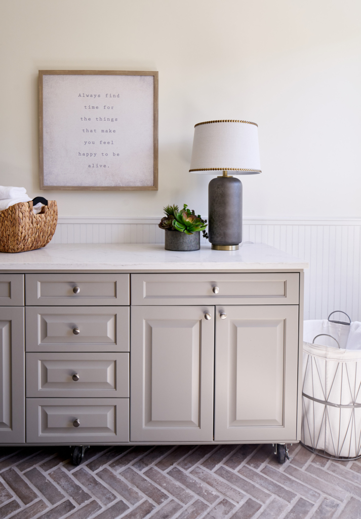 Fresh laundry room cabinets look beautiful against the custom herringbone brick floor.