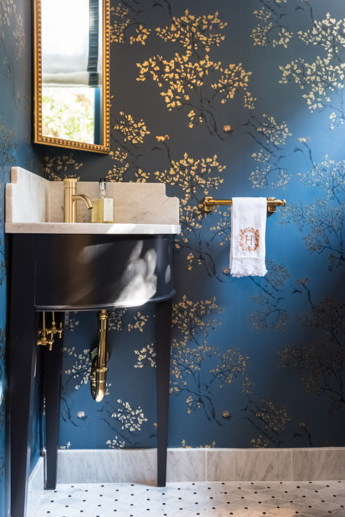 Powder bath with dark blue "Juliette" wallpaper, with a corner pedestal sink.