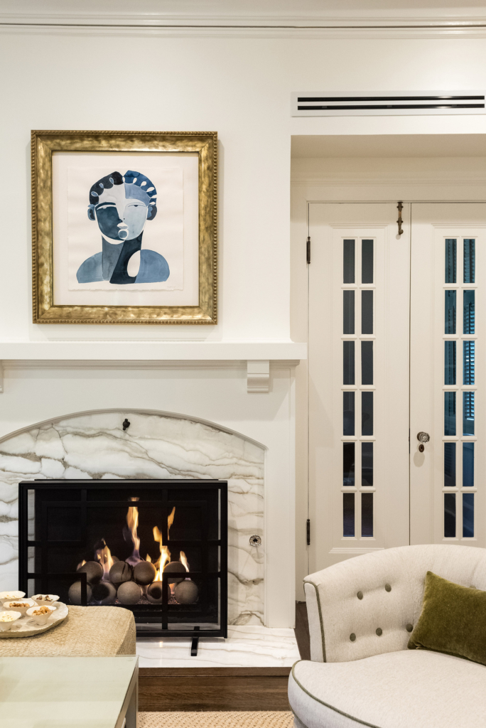 The transitional-style family room features clean white walls, swivel chairs and a welcoming fireplace.