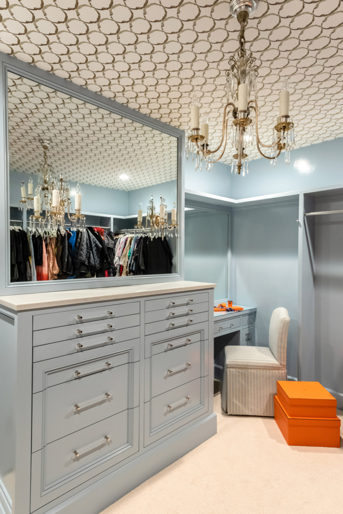 The master bedroom closet features cabinets in a soft gray-blue, with a classic wallpapered ceiling.