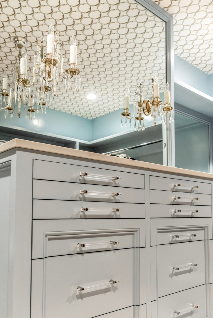 Master bedroom closet with cabinets in a soft gray-blue, a wallpapered ceiling, and special touches like the lucite drawer pulls.