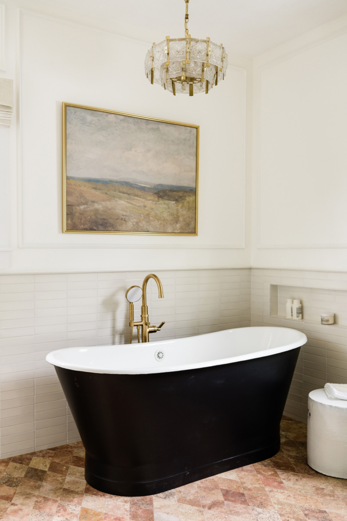 A beautifully updated primary, featuring a striking black tub and crisp wainscoting in Farrow and Ball "Skimming Stone".