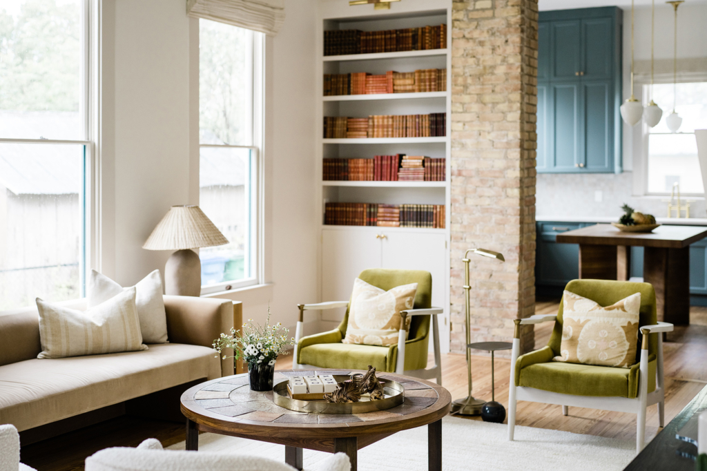 Living room with vibrant green chairs offering a view into the blue-and-white kitchen.