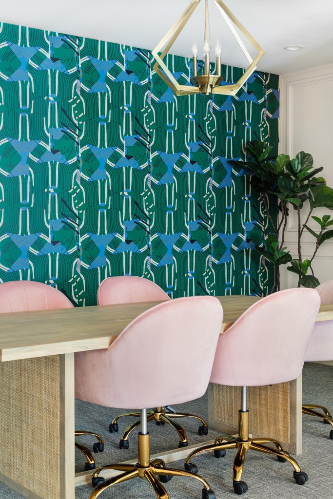 Multi-purpose study and meeting room with blue-green wallpaper and playful pink chairs for a vibrant, creative atmosphere.