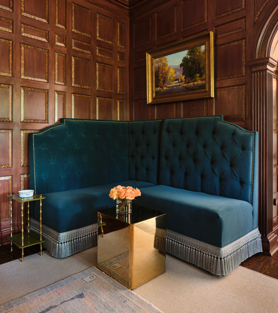 A paneled room off the foyer features custom woodwork and a striking blue banquette sofa, blending timeless craftsmanship with tailored comfort.