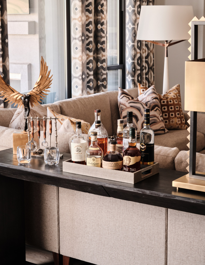 Console table styled with bar accessories in this warm contemporary living room.
